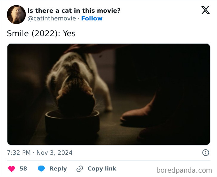 A cat in cinema, specifically from the movie Smile (2022), eating from a bowl with a hand petting its back.