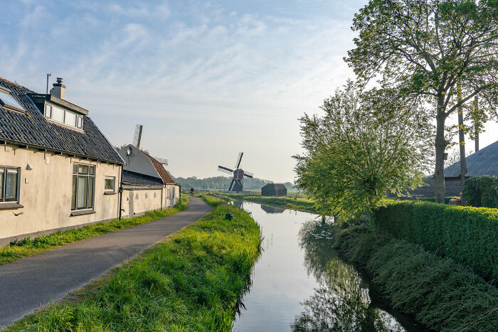 Rural scene with a windmill, canal, and houses, illustrating childhood risks and lack of survival instincts outdoors.
