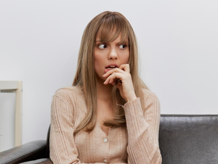 Worried woman sitting on couch, reflecting on boyfriend's female friend and her closeness to his family. Worried woman sitting on couch, reflecting on boyfriend's female friend and her closeness to his family.