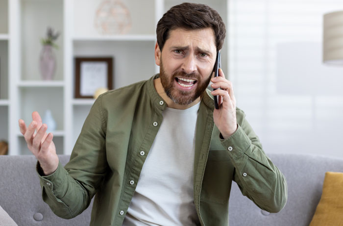 Um homem ao telefone, parecendo zangado e frustrado, suspeitando de uma criança secreta.