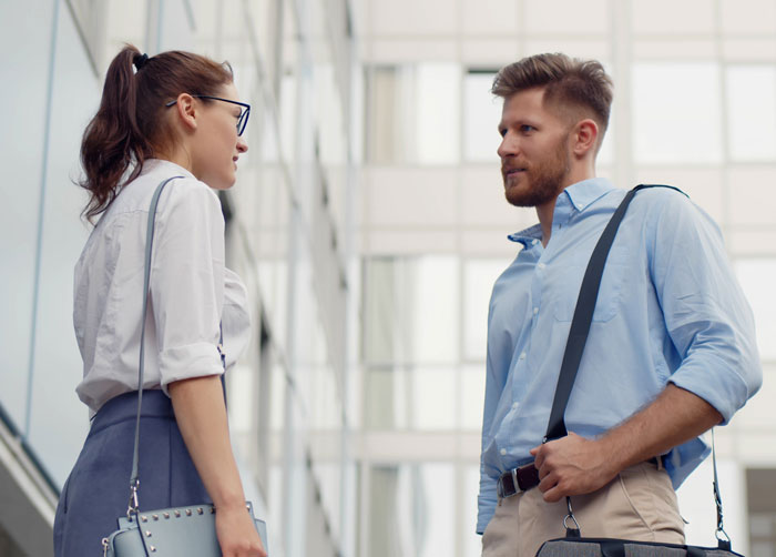 A woman and man having a serious conversation in an office setting about things women are tired of explaining to men