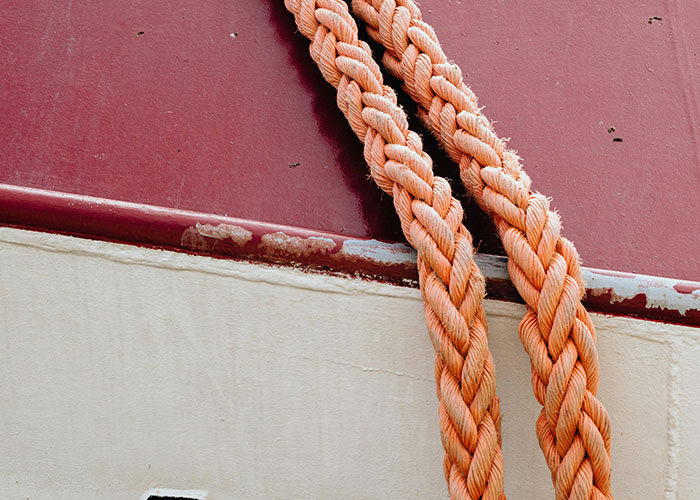 Close-up of thick orange ropes on a boat hull illustrating dangers that are a lot more dangerous than they seem.
