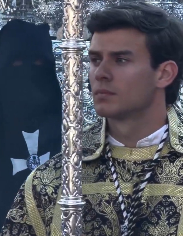 Jovem com um manto ornamentado segurando um cajado de prata durante a procissão da Páscoa espanhola, vinculado ao burburinho da Internet sobre a gostosa da Páscoa espanhola.