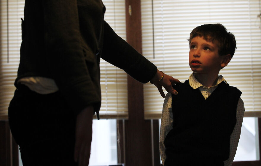 Young boy looking up at adult with a hand on his shoulder, illustrating feeling like an outcast in the family narrative.