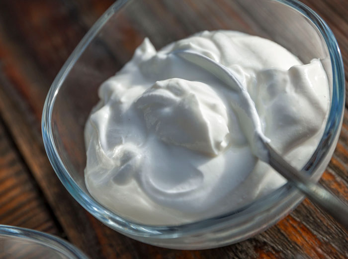 Glass bowl of creamy white yogurt with a spoon, a sweet act of revenge against toxic bosses.