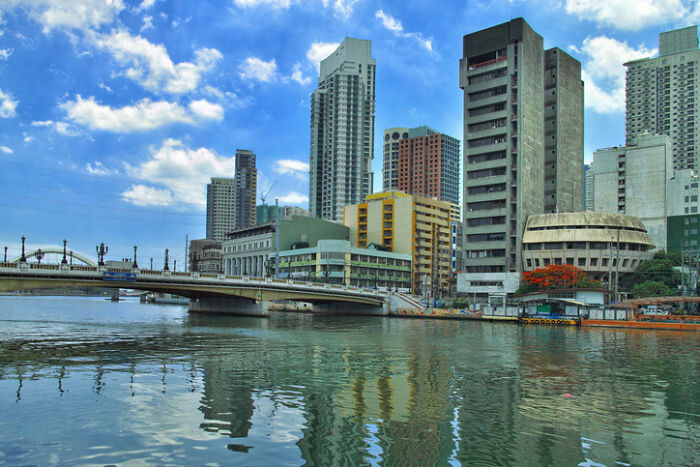 Dynamic city scene by a river with a bridge & varied architecture, indicative of regions with the worst work-life balance.