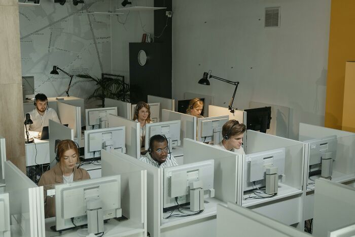 Employees in an office working in cubicles, wearing headsets. Highlights common workplace incidents and daily routines.
