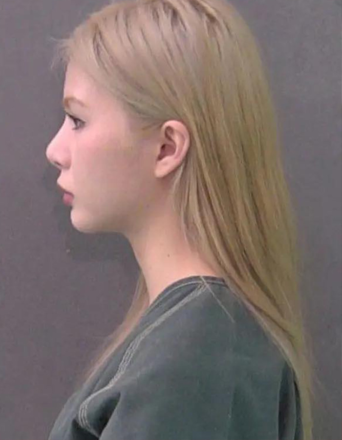 Foto de uma professora substituta loira de perfil, vestindo uma camisa verde, enfrentando acusações.