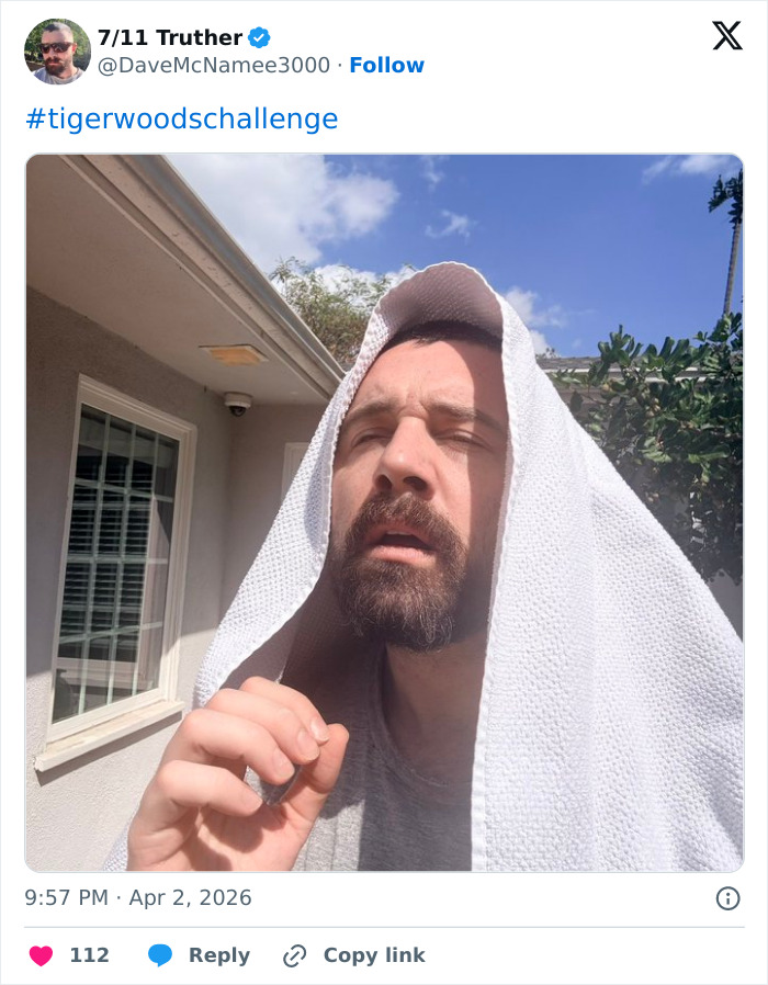 Man with a beard and towel over his head outdoors, participating in the Tiger Woods challenge with humorous expression.