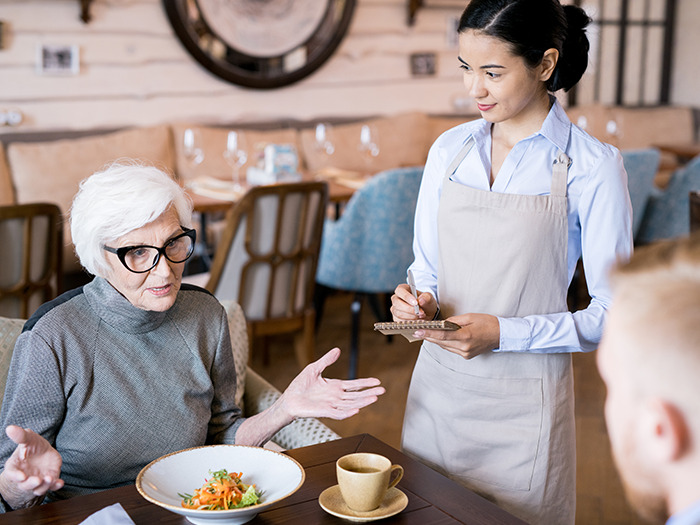 Elderly woman speaking to a restaurant staff member, illustrating rude customers who learned not to mess with staff.