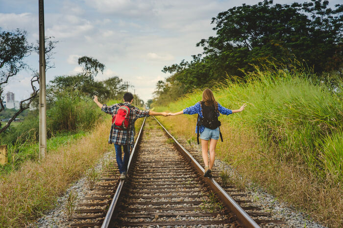 Two kids walking on railroad tracks holding hands, illustrating childhood dumbest things and lack of survival instincts.