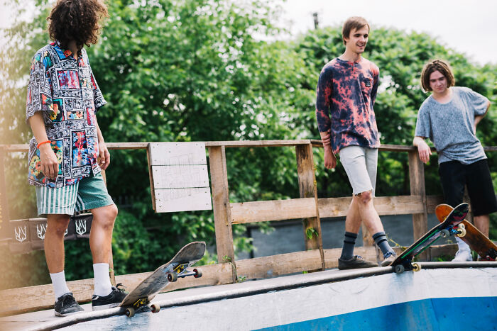 Three young men at a skate park with their skateboards, illustrating stories of karma in various satisfying forms.