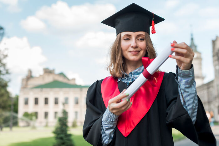 Young woman in graduation attire holding diploma outdoors, symbolizing inspiring comebacks and thriving success.