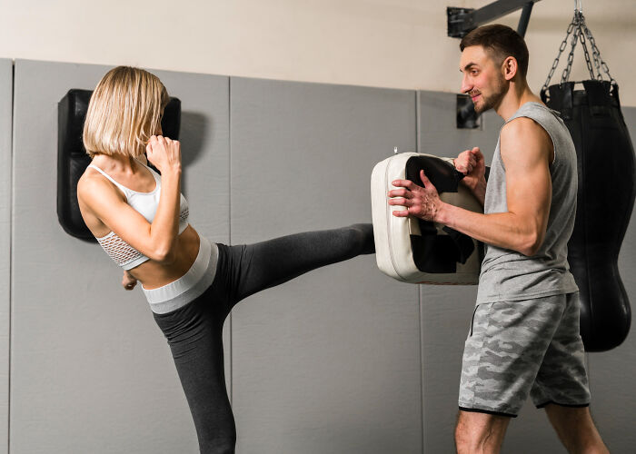 Woman practicing kickboxing with a trainer, showcasing red flags of disastrous first dates and instant regret moments.