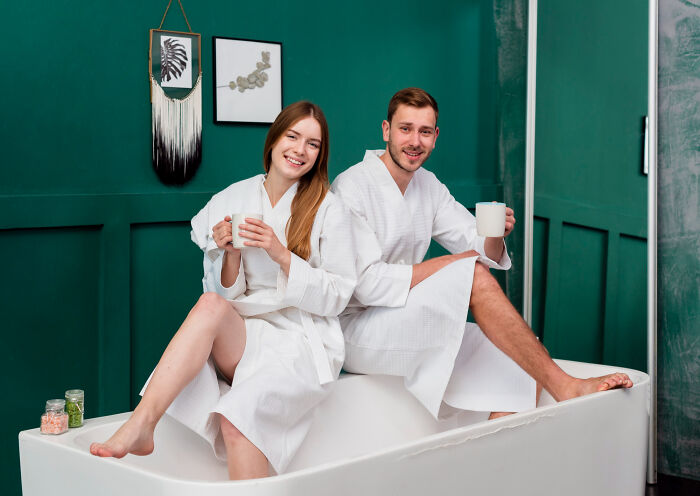 Couple in white robes sitting in bathtub with mugs, representing awkward moments from people who left mid-date.