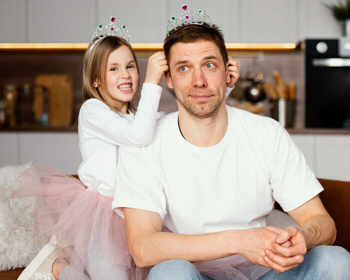 Young girl adjusting tiara on man's head, both in casual clothes, highlighting first dates red flags and instant regret.