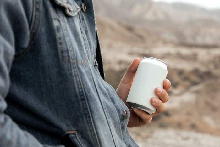 Person in a denim jacket holding a blank white can, representing unusual items TSA has confiscated from travelers.