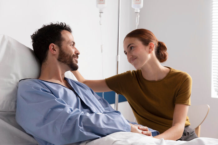 Smiling patient in a hospital bed, comforted by a woman. Medical Workers witness such important moments in care.
