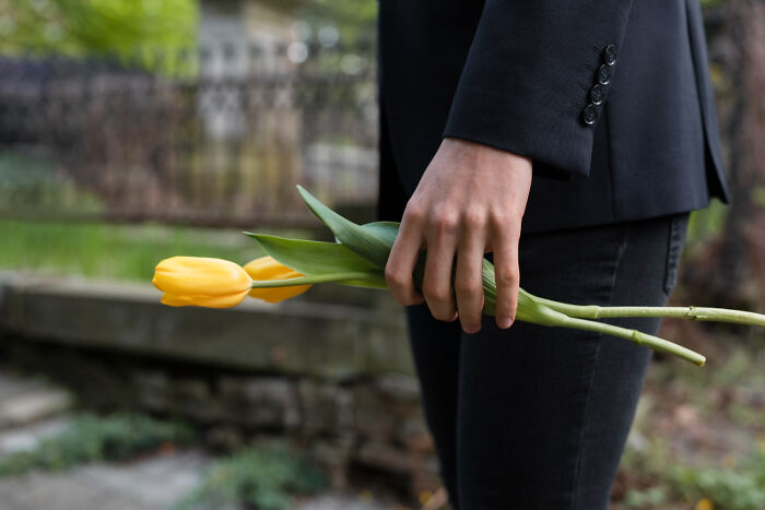 Person in black holding yellow tulips, symbolizing moments of being a good person ending in total betrayal and shock.