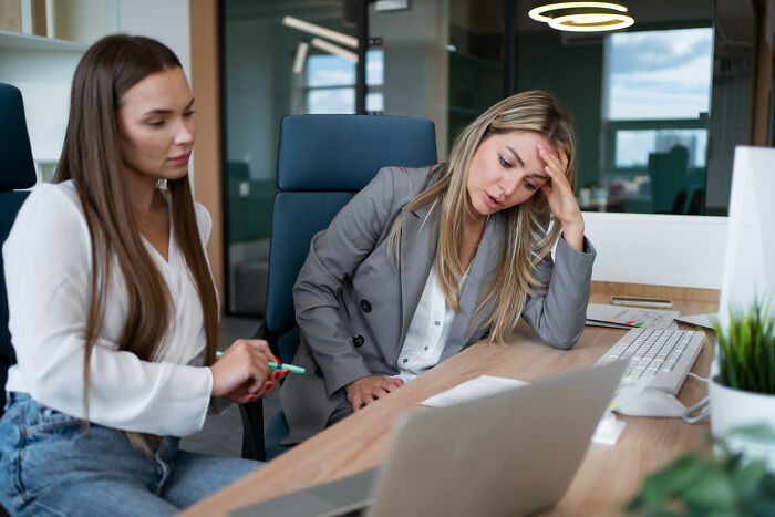 Two women in an office discussing work, showcasing determination and inspiring comebacks for thriving success.