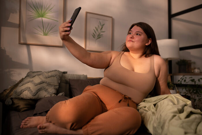 Woman relaxing on a couch taking a selfie, illustrating random facts people learned about their bodies after doctor visits.