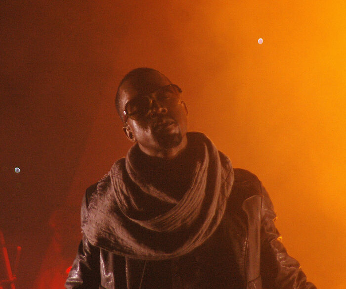 Kanye West se apresentando no palco com iluminação laranja em meio à polêmica do Wireless Festival e discussões sobre retirada de patrocinadores.