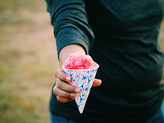 Person holding a colorful shaved ice dessert cone, illustrating customer service moments with rude customers and staff interactions.