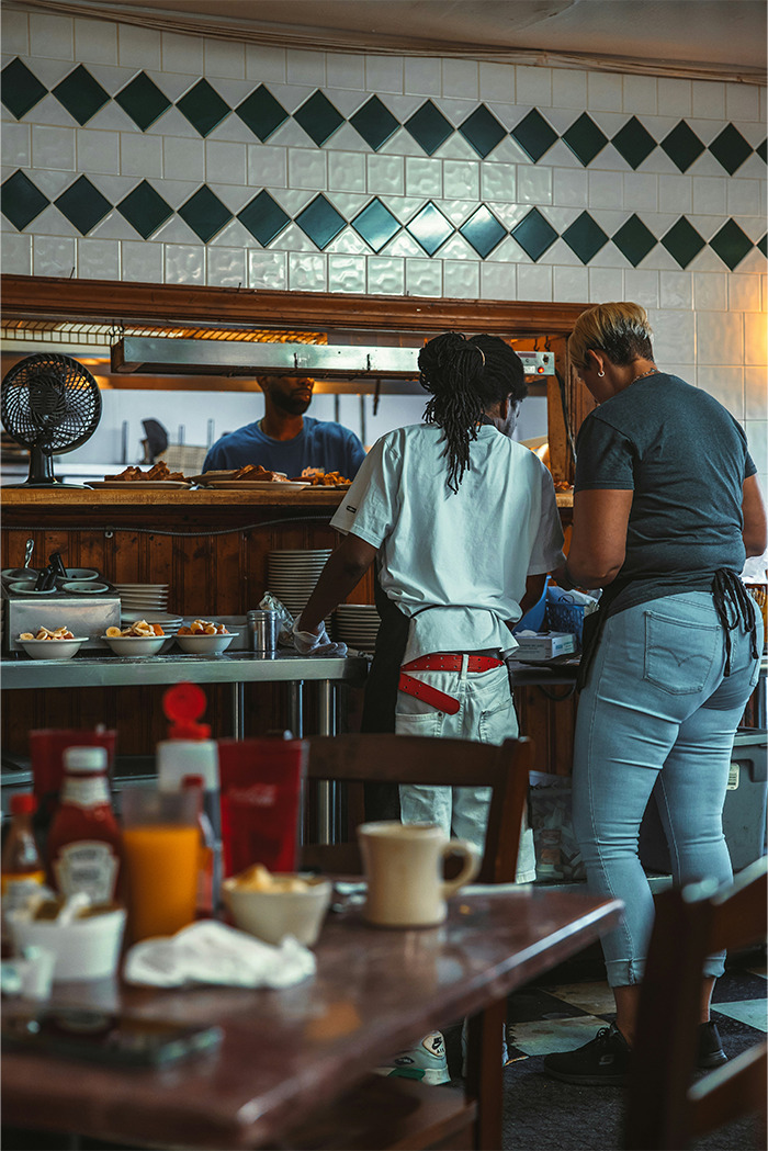 Two restaurant staff handling orders behind the counter, illustrating rude customers learning not to mess with staff.