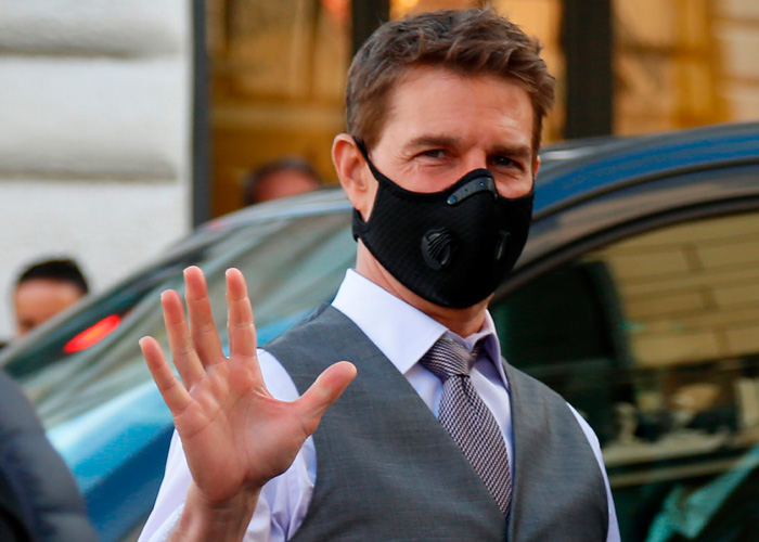 Tom Cruise wearing a black face mask and grey vest, waving. Things that went down 6 years ago, completely unreal.
