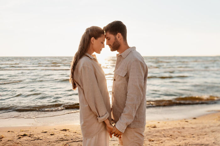 Couple holding hands and facing each other on the beach at sunset, illustrating themes of being a good person.
