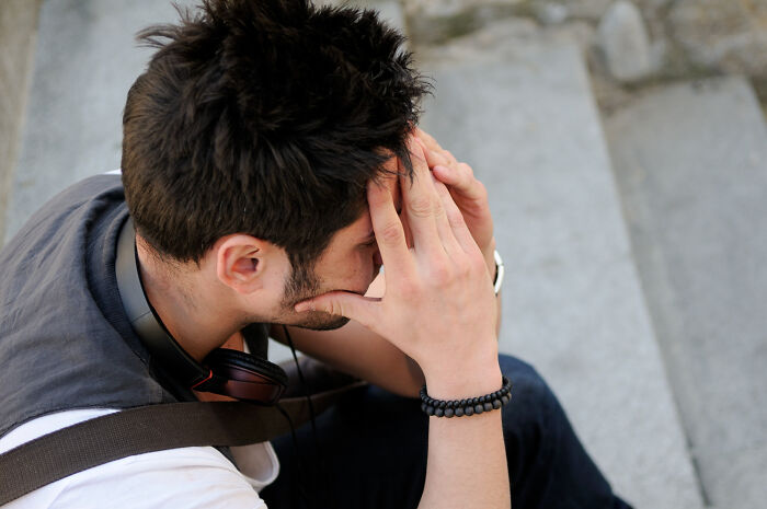 Distressed man, head in hands, sitting on steps. Captures the painful impact of friendship betrayals.