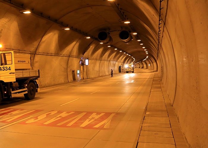 Inside a dimly lit tunnel, a worker stands by a maintenance truck. Exclusive access reveals the massive infrastructure.