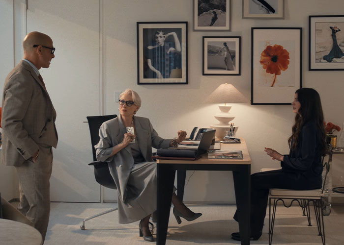 Three people in a stylish office setting, depicting the reality of working for Vogue icon Anna Wintour.
