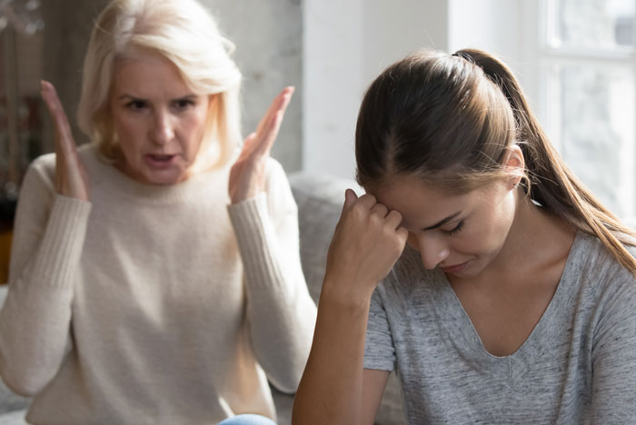 Uma mulher mais velha gesticula com raiva para uma jovem que parece perturbada. Esta imagem está relacionada a regras de não rebatida.
