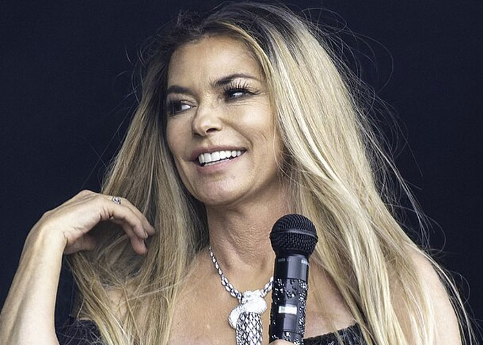 Woman with long blonde hair holding a microphone, smiling during an event about beloved celebrities not that nice in real life.