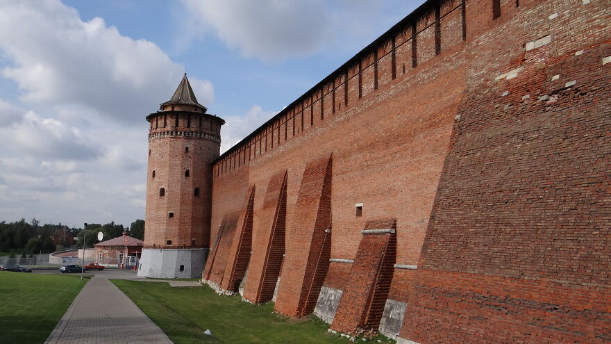 A massive red brick wall and tower under a cloudy sky, displaying tough security of historical places off-limits.