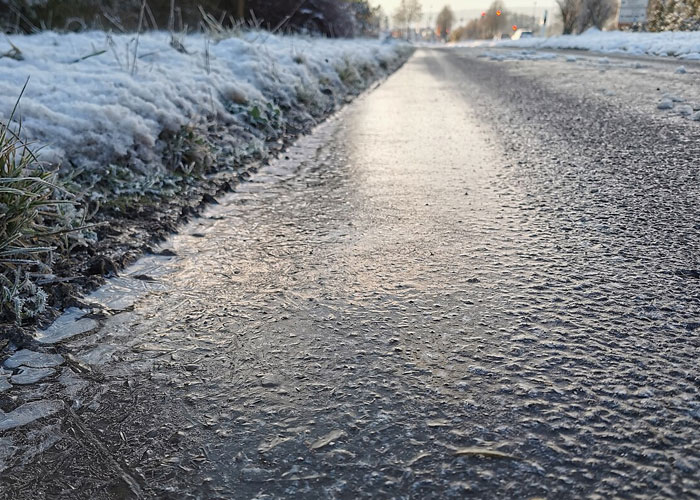 Icy road surface with frost and snow on the side, illustrating dangers that seem minor but are actually harmful.
