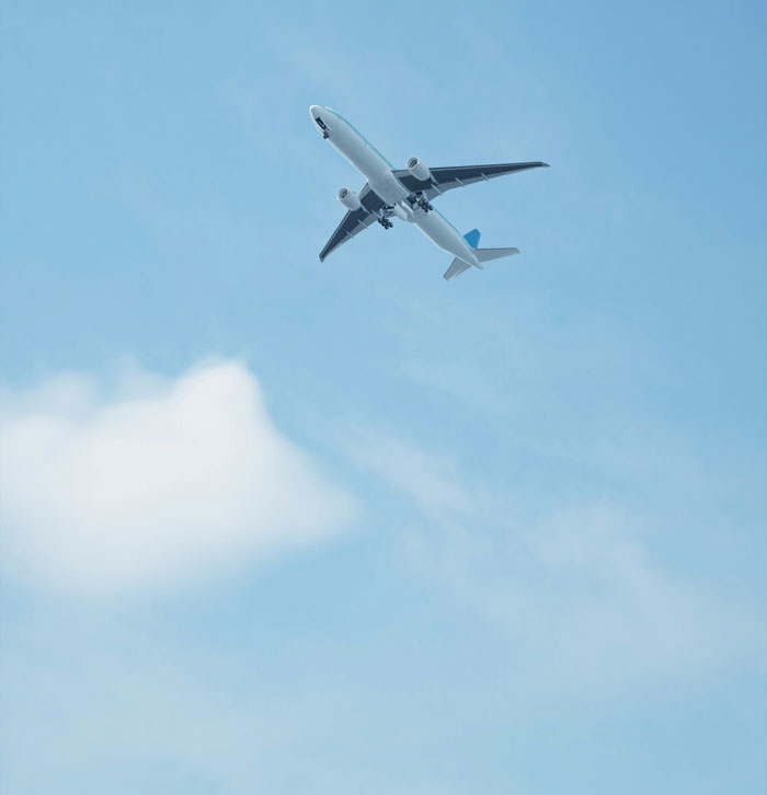 Commercial airplane flying in a clear blue sky above light clouds, symbolizing oversleeping turning into a complete nightmare.