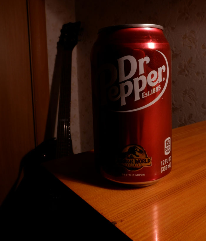 Dr Pepper can on a wooden table with a guitar in the dim background illustrating companies' social media post fails.
