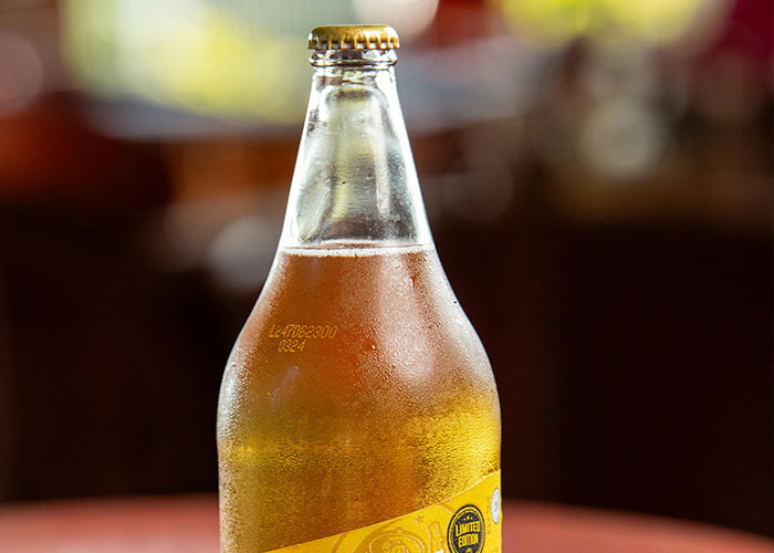 Close-up of a cold beer bottle with condensation, illustrating consumer spending trends linked to the economy's performance.