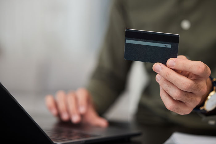 A person holds a credit card, using a laptop. A moment when someone saw just how dumb the person they're dating was.