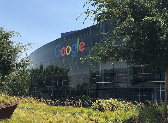 Google headquarters building with reflective glass windows surrounded by trees and grass, illustrating events by birth year.