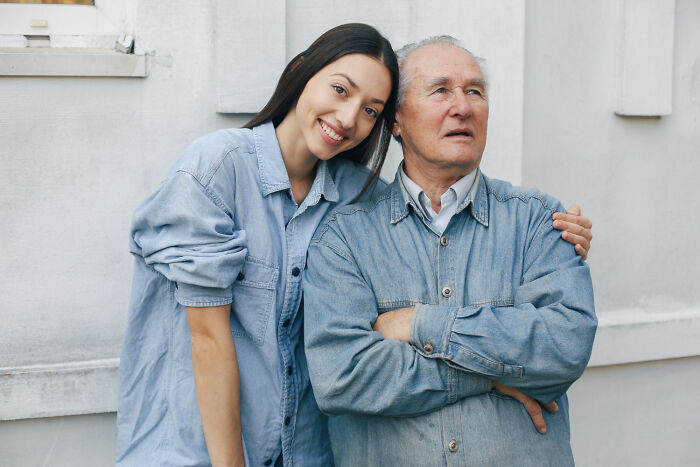Young woman smiling and leaning on an elderly man wearing denim jackets, showing kindness despite betrayal fears.