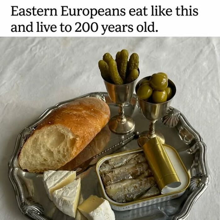 Silver tray with bread, cheese, pickles, olives, and canned fish representing food memes humor about Eastern European eating habits.