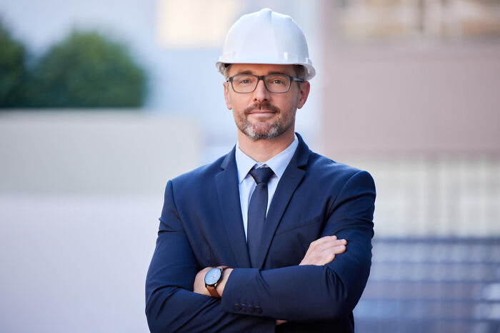 Professional man in suit and hard hat standing confidently outdoors, symbolizing random life decisions leading to the right place.