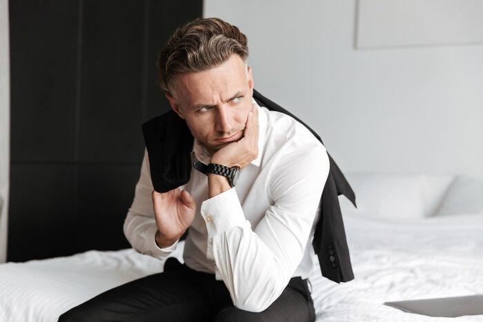 Man in formal clothes looking worried and thoughtful, symbolizing guests witnessing a future breakup at a wedding.