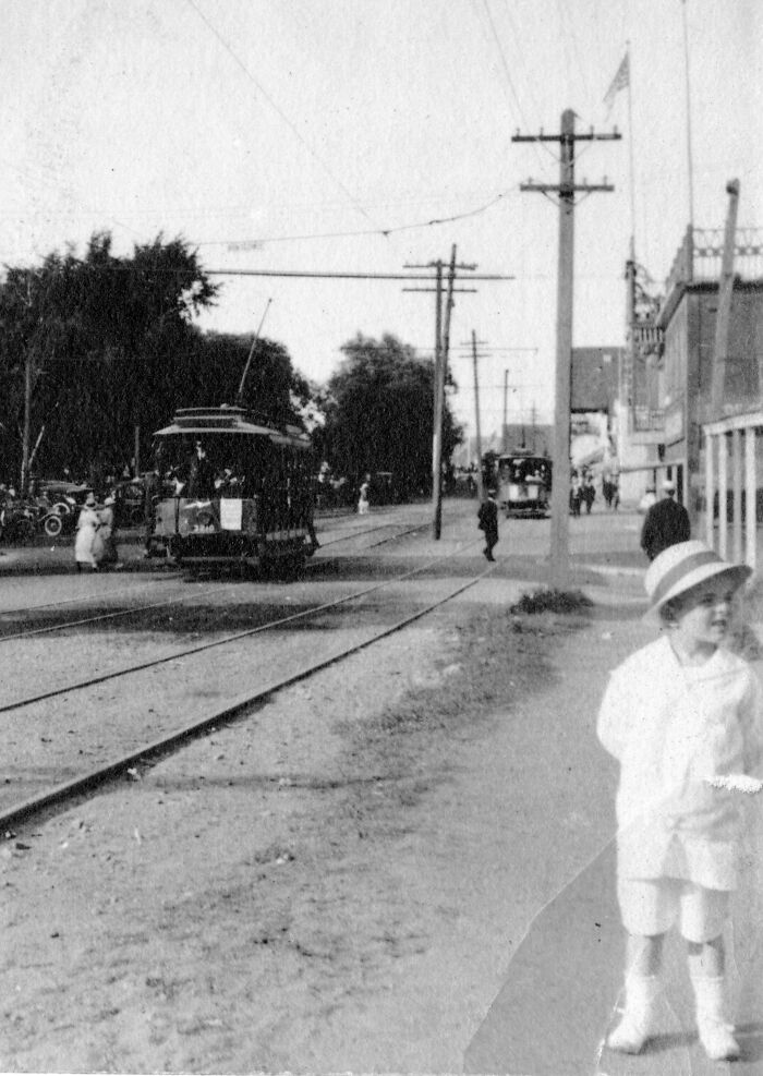 Early 1900s rare and interesting photo shows a streetcar on tracks with people and buildings along the road.
