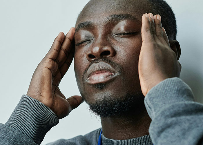 Stressed man holding his head with eyes closed, reflecting frustration over entitled mom assuming food will be bought for kids.