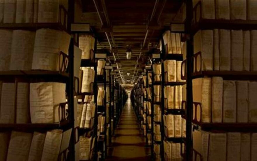 Long, dimly lit archive aisle filled with ancient documents on shelves, protected by tough security.