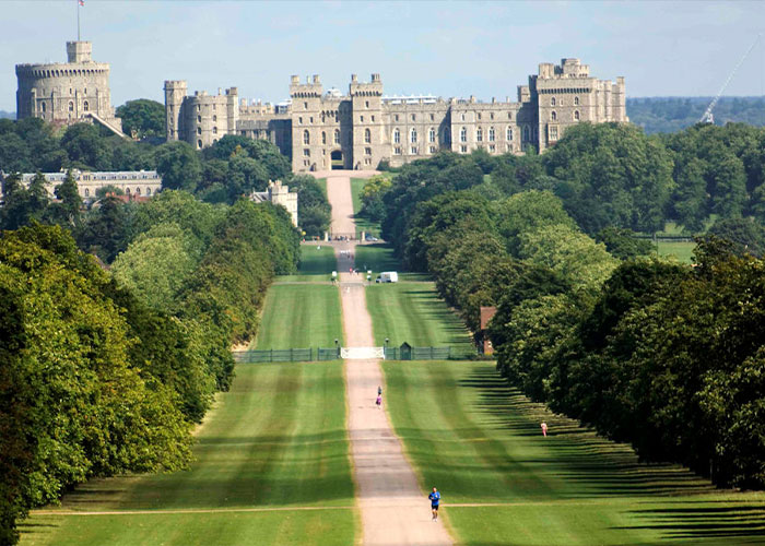 Wide view of Windsor Castle and its long tree-lined driveway, related to Harry and Meghan Markle turbulent dynamic.